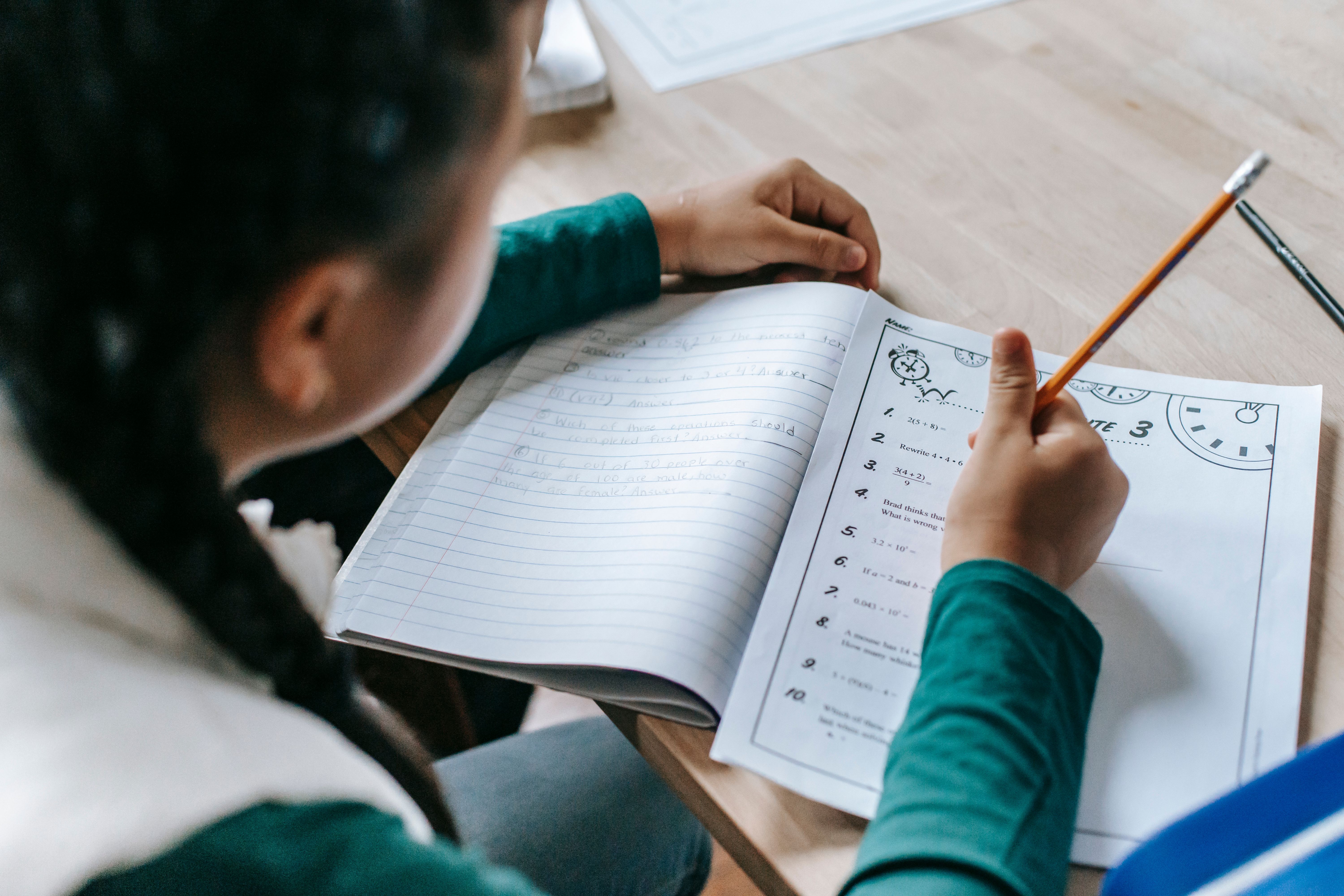 Student completing homework in a notebook at a classroom desk